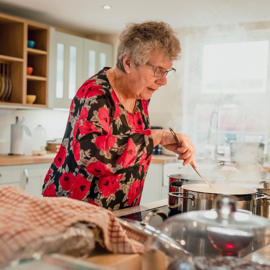 Elderly lady cooking in kitchen