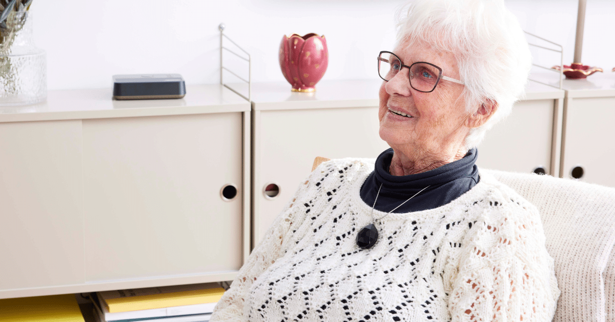 Lady with white hair smiling wearing Ellis pendant alarm