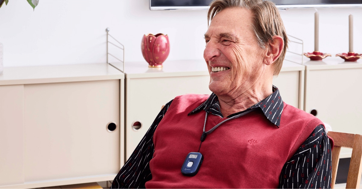 Man smiling in chair wearing pendant