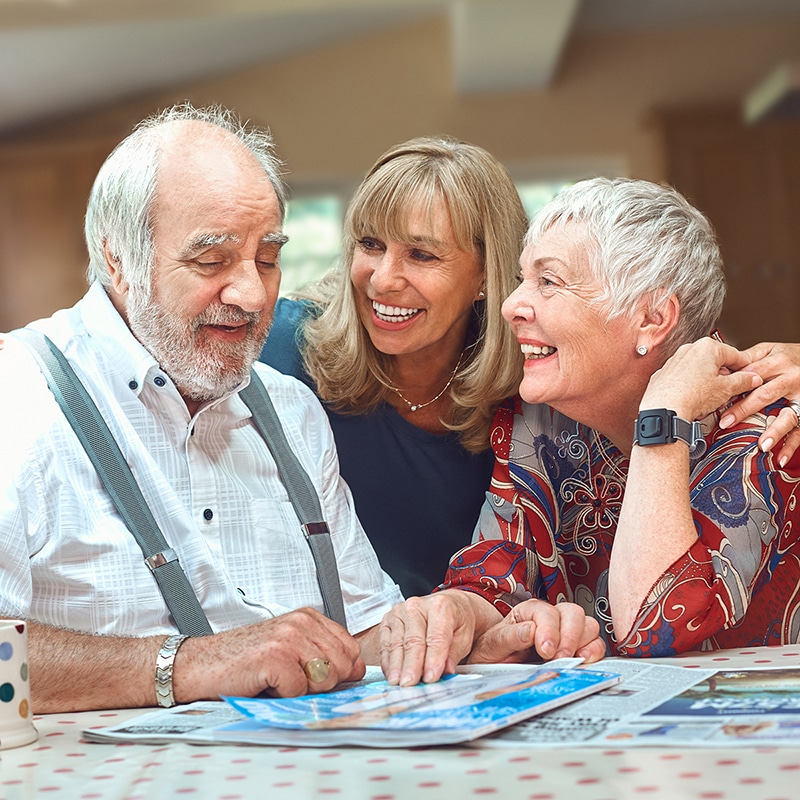 An elderly couple smiling with their daughter